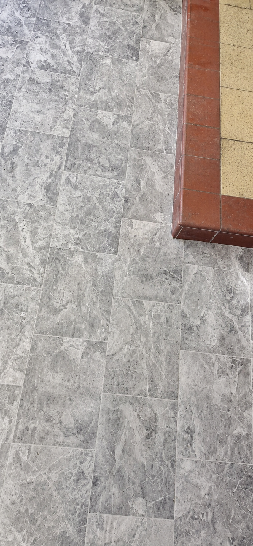 Detail of vinyl flooring fitted neatly beside a tiled hearth