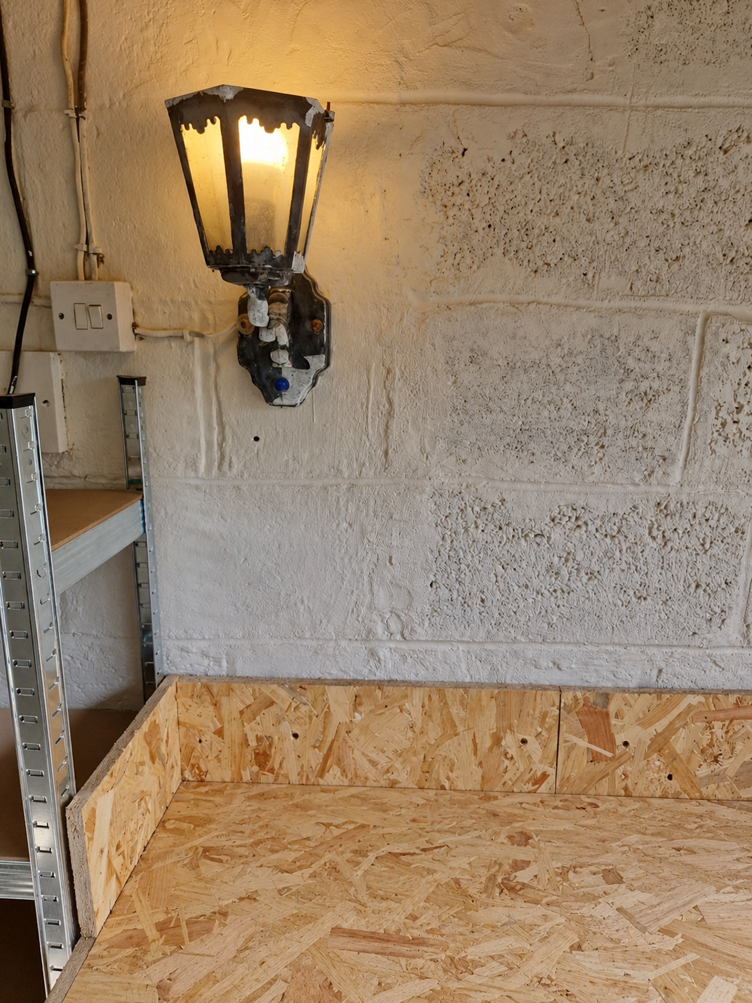 Garage workshop corner with the repaired wall and OSB workbench